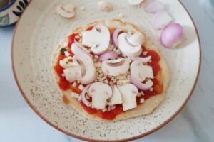 Adding Some cheese and toppings on the tortilla Pizza